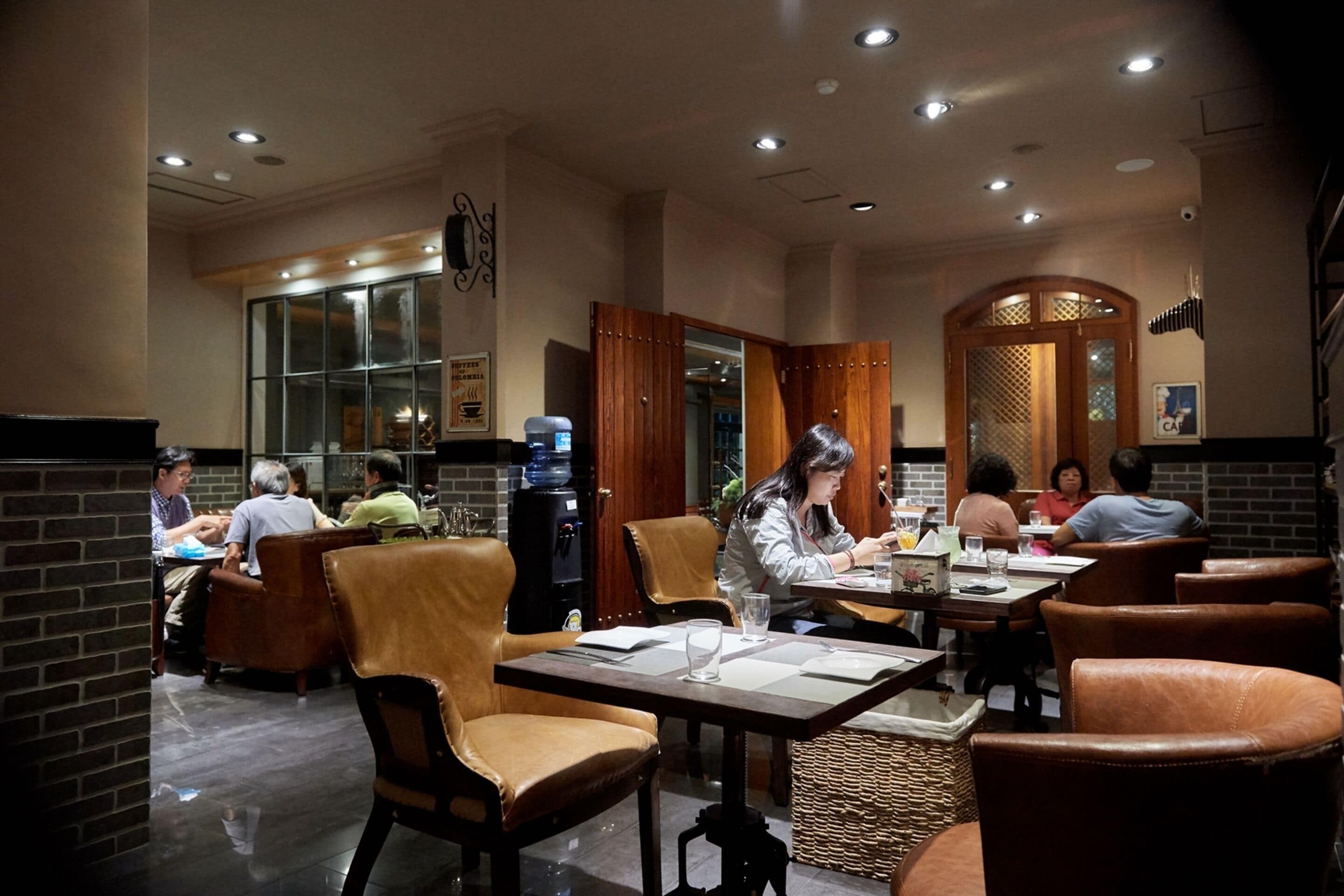 Un restaurante con sillas de cuero, mesas y una pared de ladrillo.