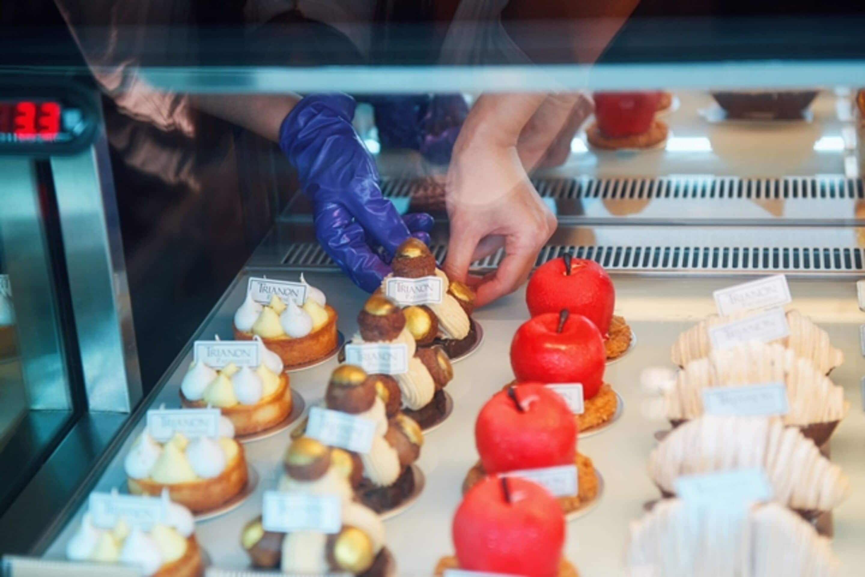 Een vitrine met diverse gebakjes en desserts, waaronder truffels en een rode appel.