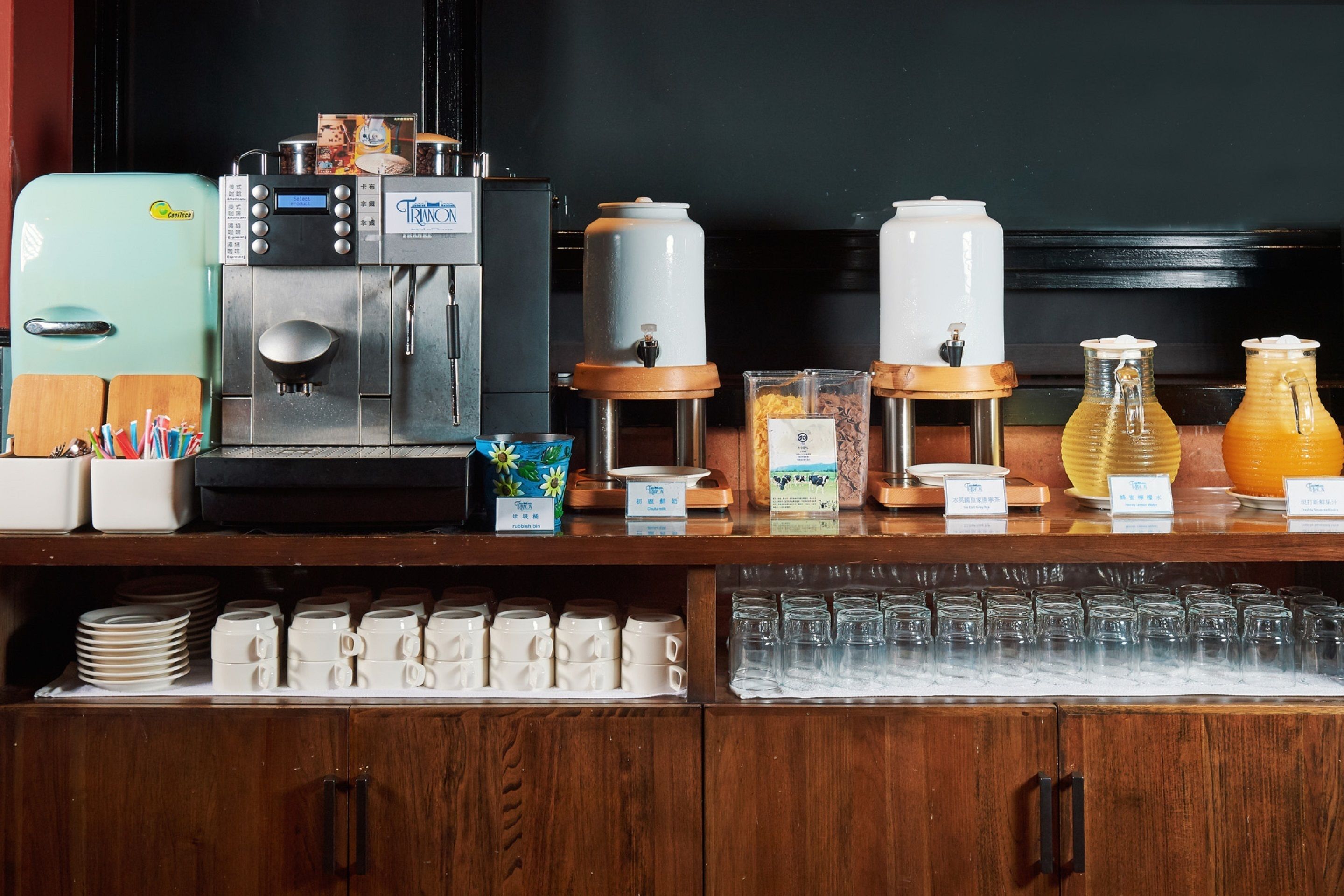 Una estación de café con cafetera, espumador de leche y varios dispensadores de café.