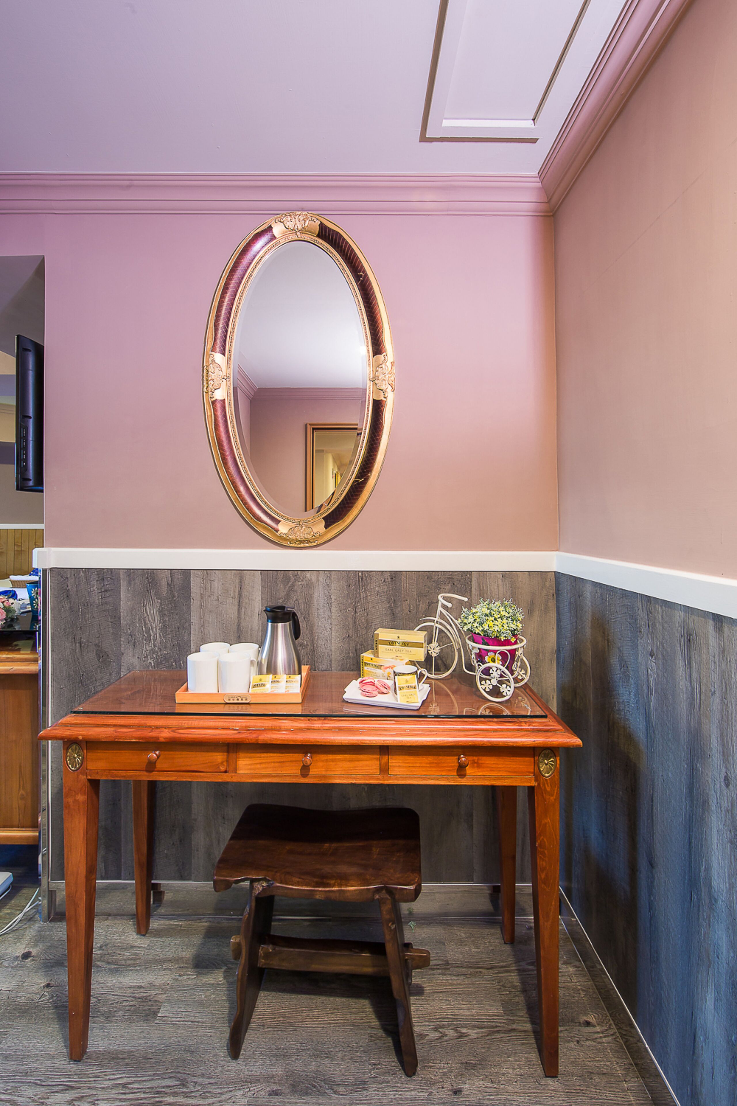 A wooden table with a mirror above it, a bench, and a tray with various items including a coffee pot and a bicycle.