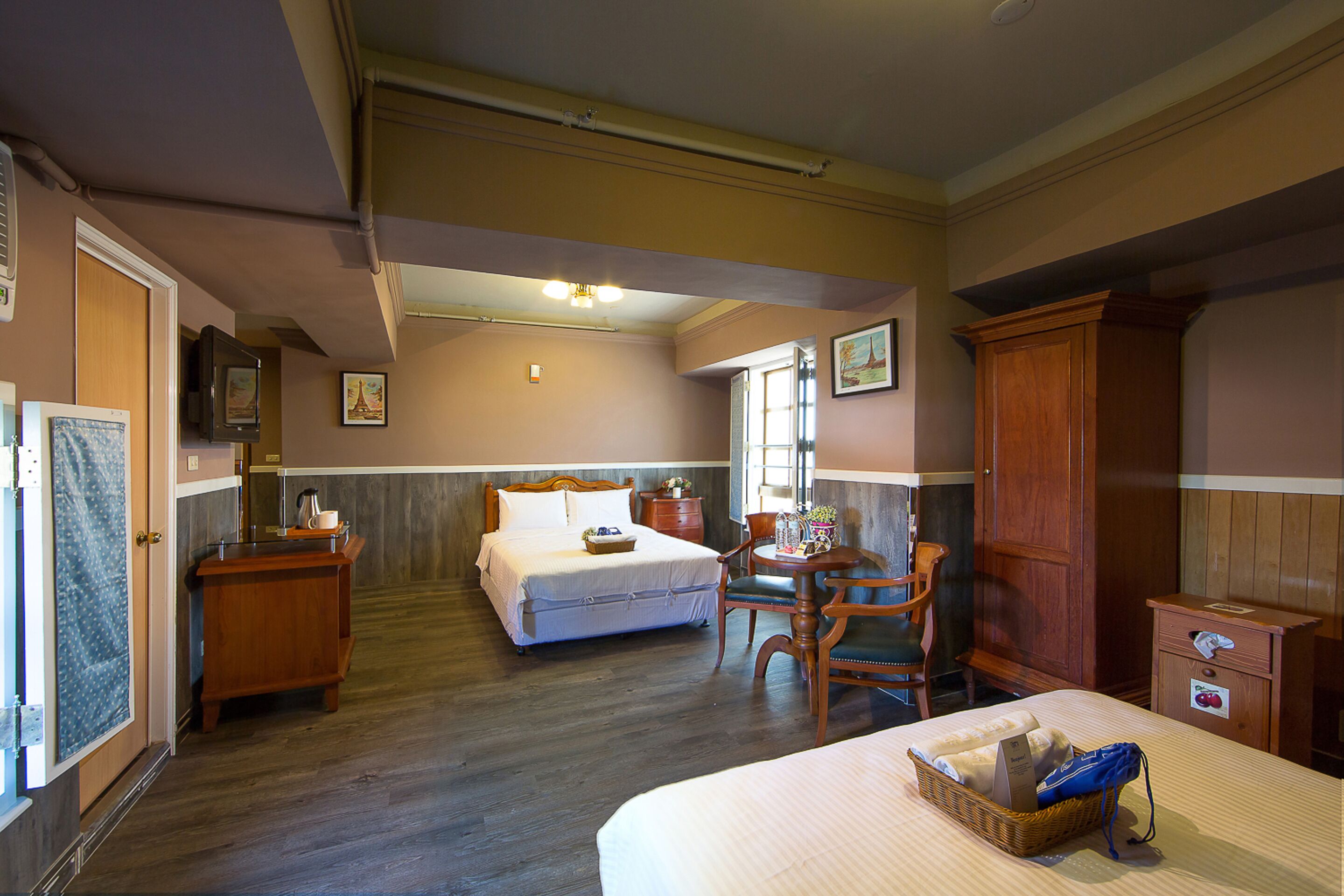 Une chambre d’hôtel avec un grand lit, un bureau, une chaise, une commode et une fenêtre.