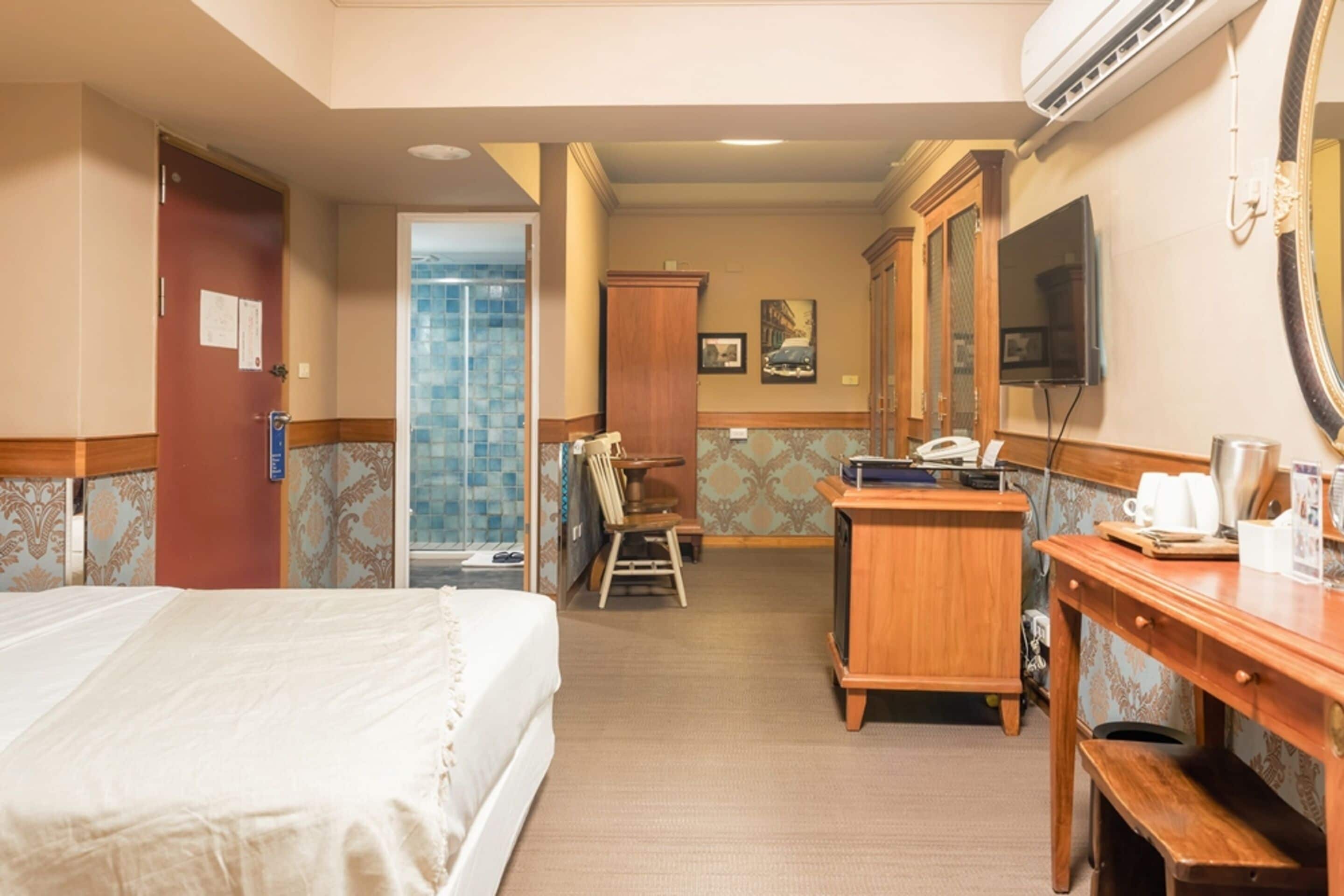 A hotel room with a bed, desk, chair, and a television.