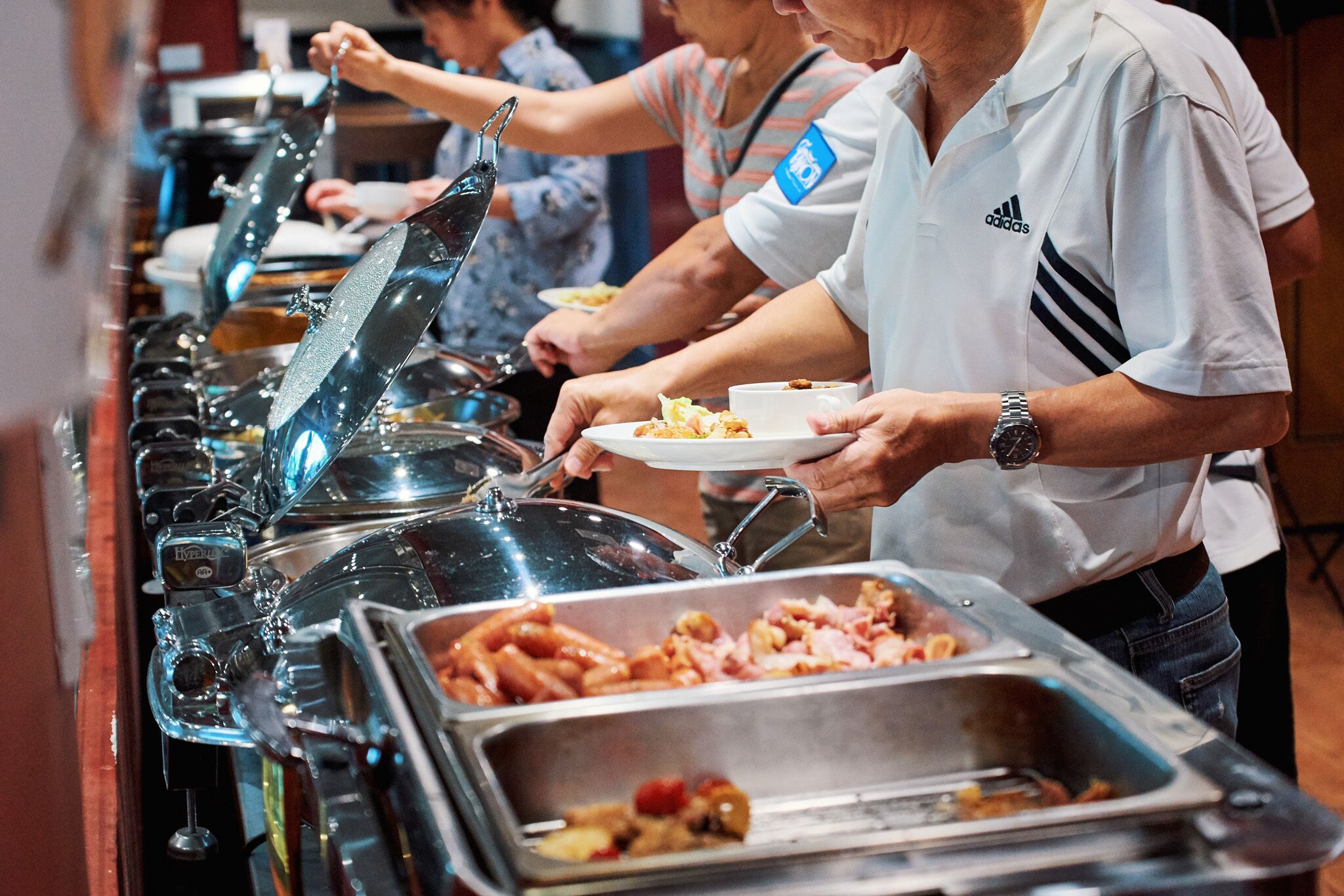 Een buffet met verschillende gerechten en een persoon die zich bedient.