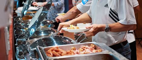 Een buffet met verschillende gerechten en een persoon die zich bedient.