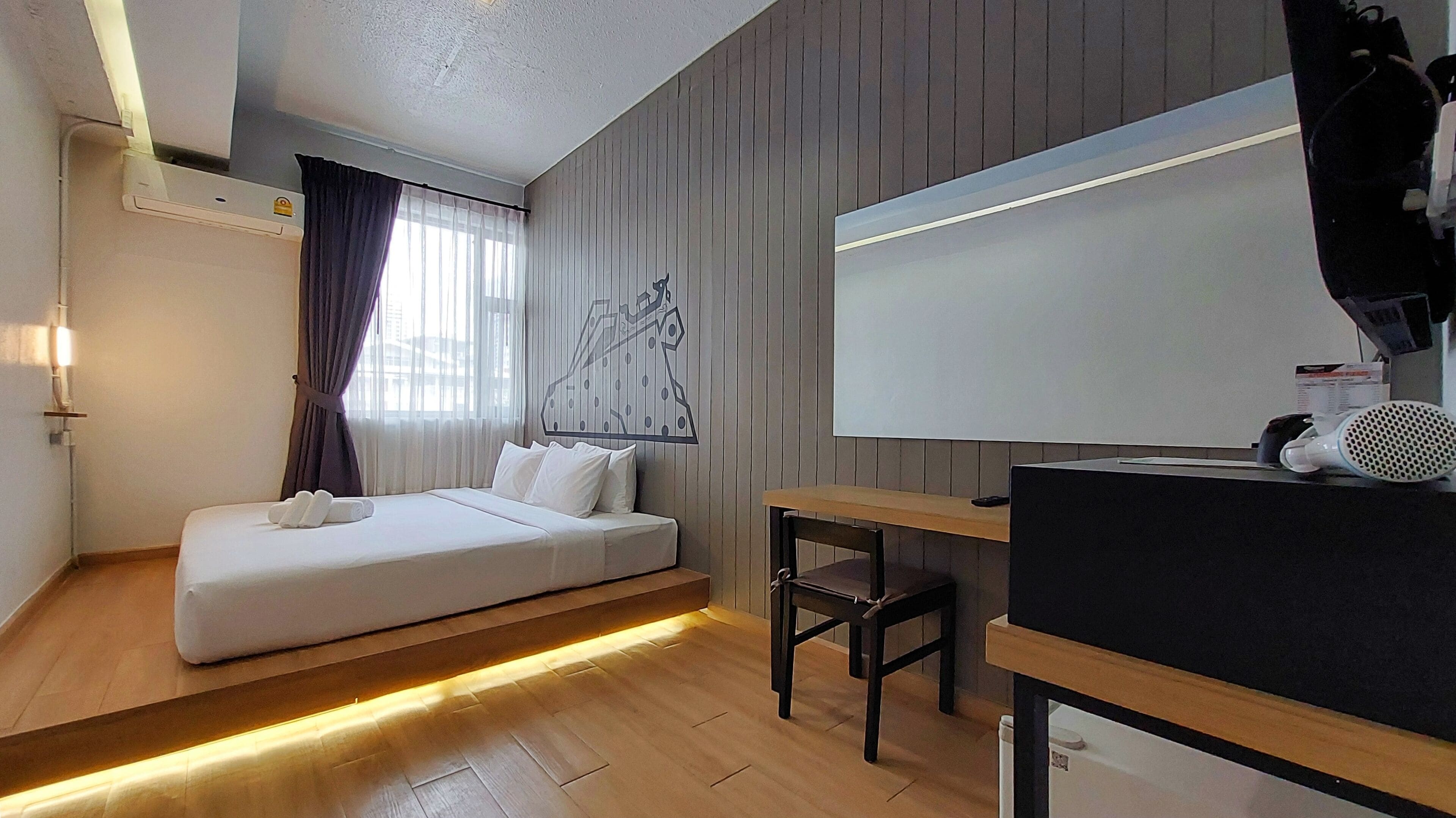 A modern hotel room with a bed, a desk, and a large window with curtains.