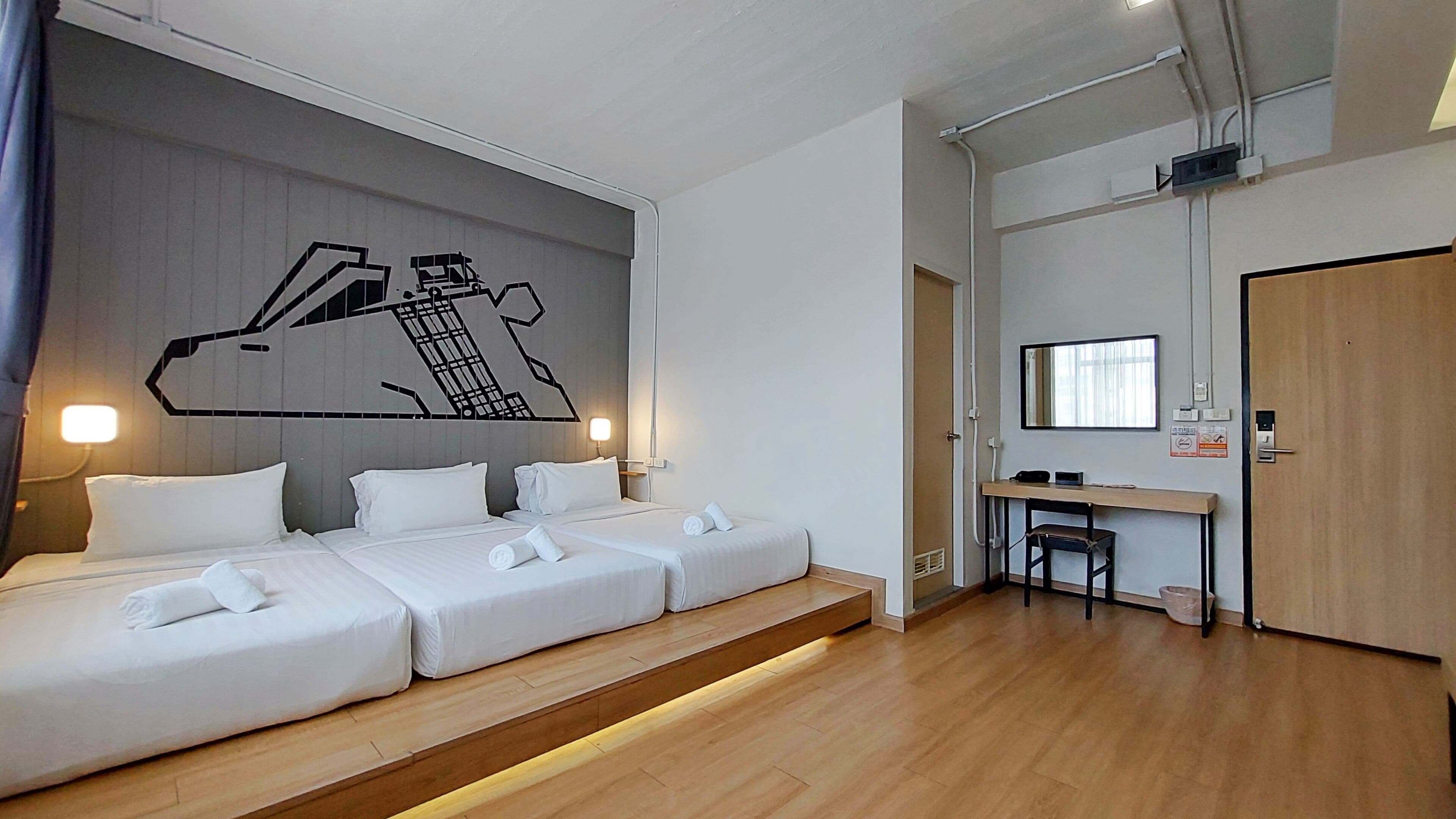 A hotel room with a bed, a desk, and a mirror.