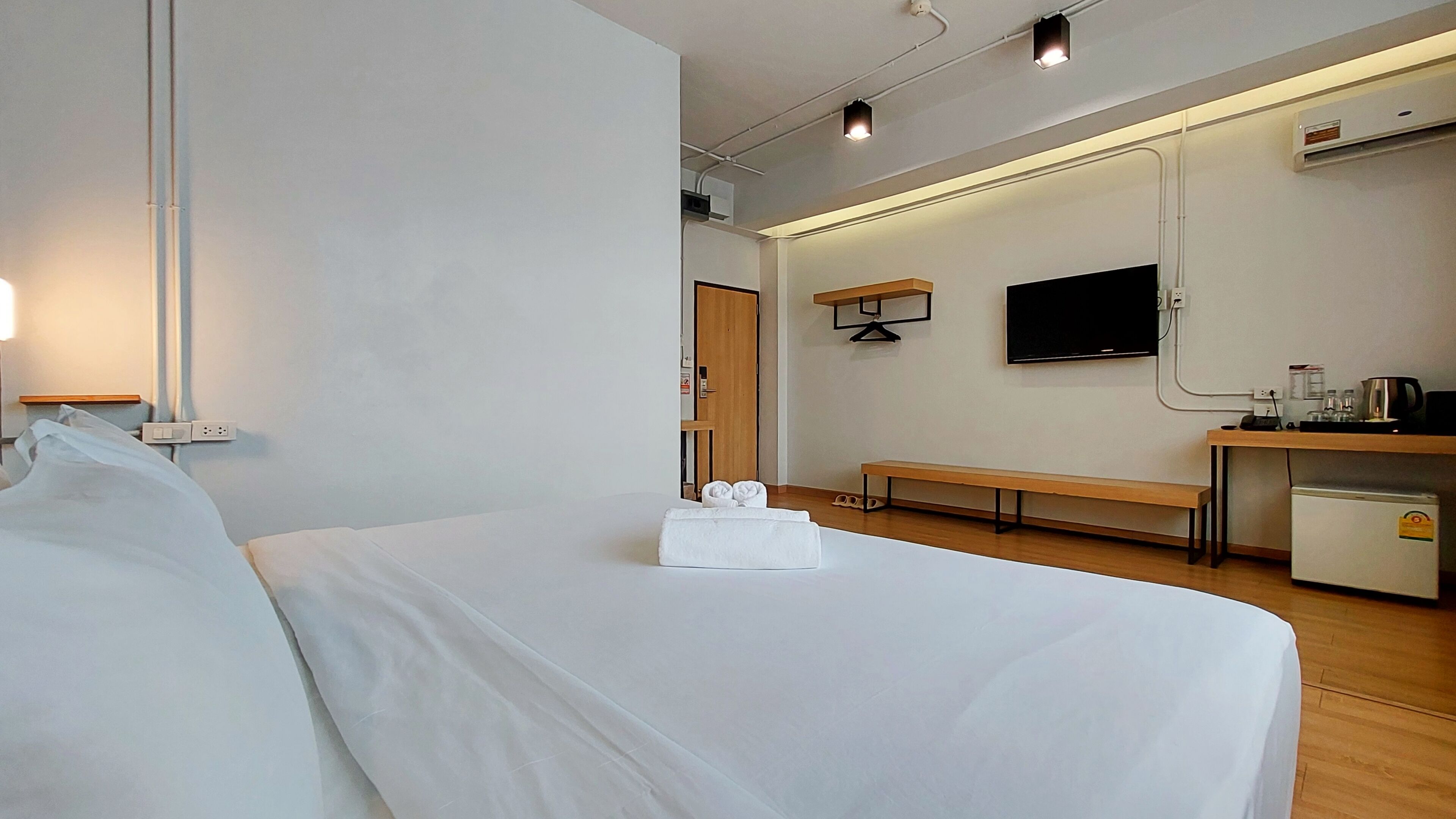 Une chambre d’hôtel équipée d’un lit, d’un banc, d’une télévision et d’une petite kitchenette.