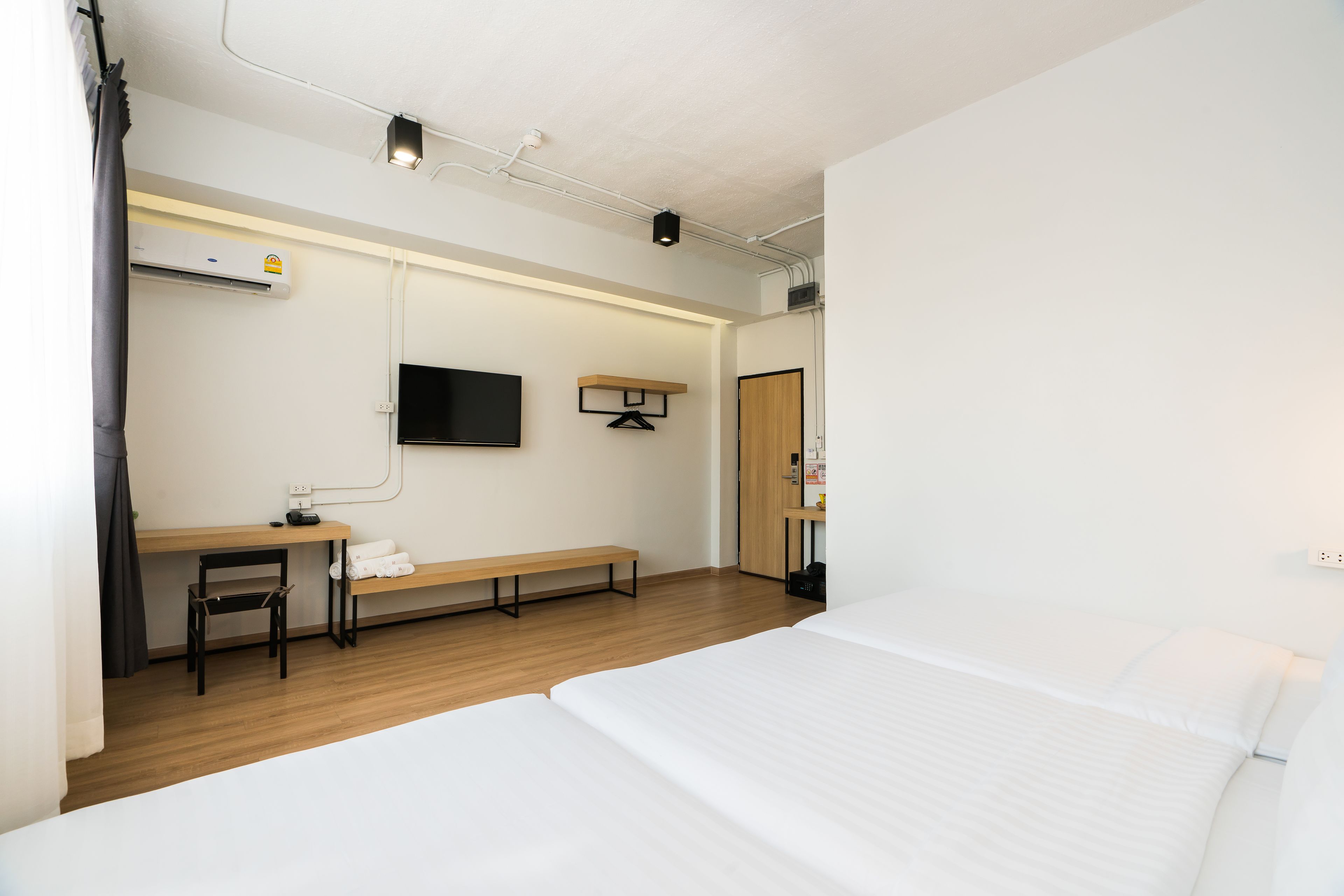 A hotel room with a bed, a desk, a chair, a TV, and a wardrobe.