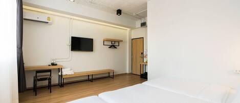 A hotel room with a bed, a desk, a chair, a TV, and a wardrobe.