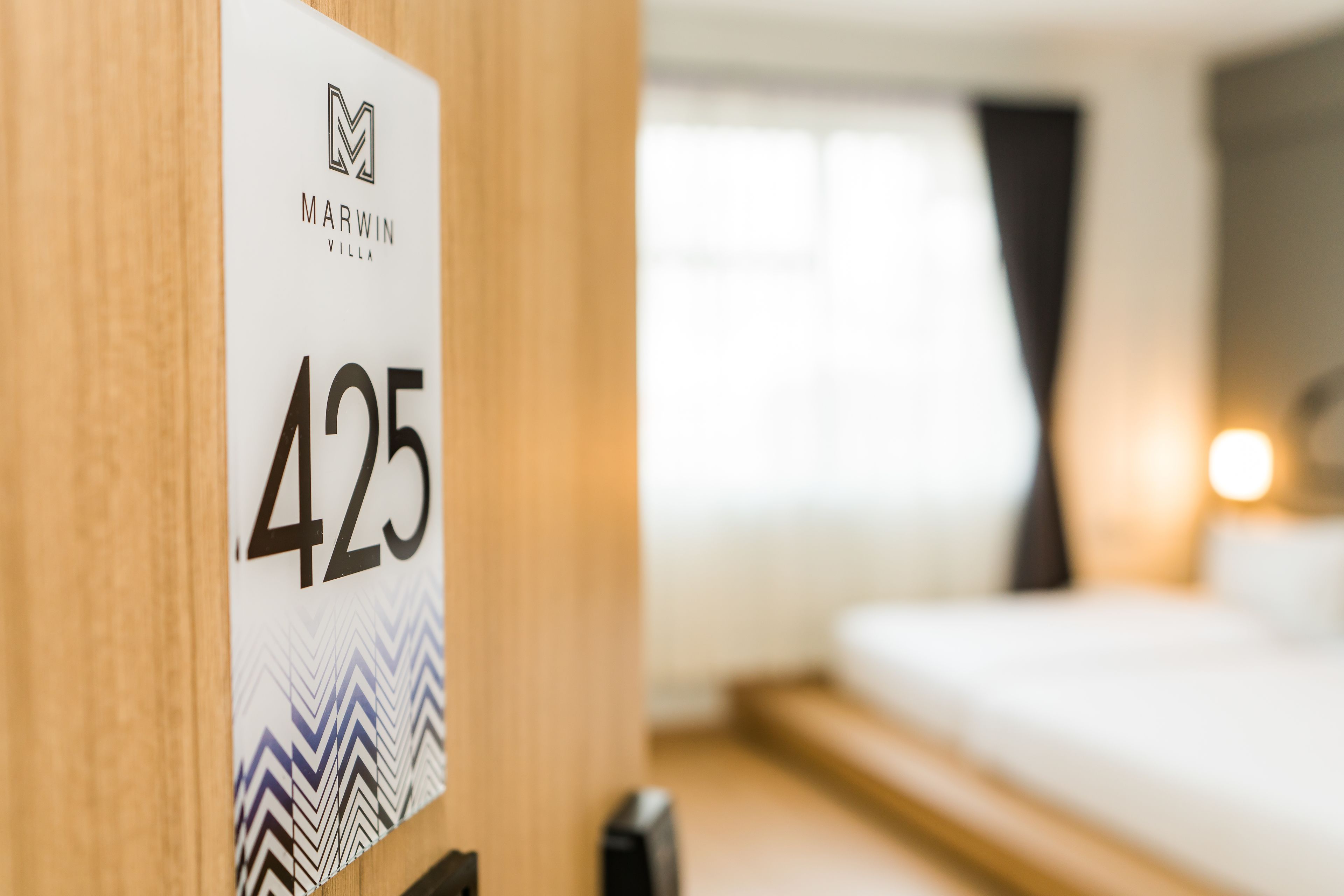 Ein Hotelzimmer mit Bett, Nachttisch und einem an der Wand befestigten Schild mit der Zimmernummer 425.