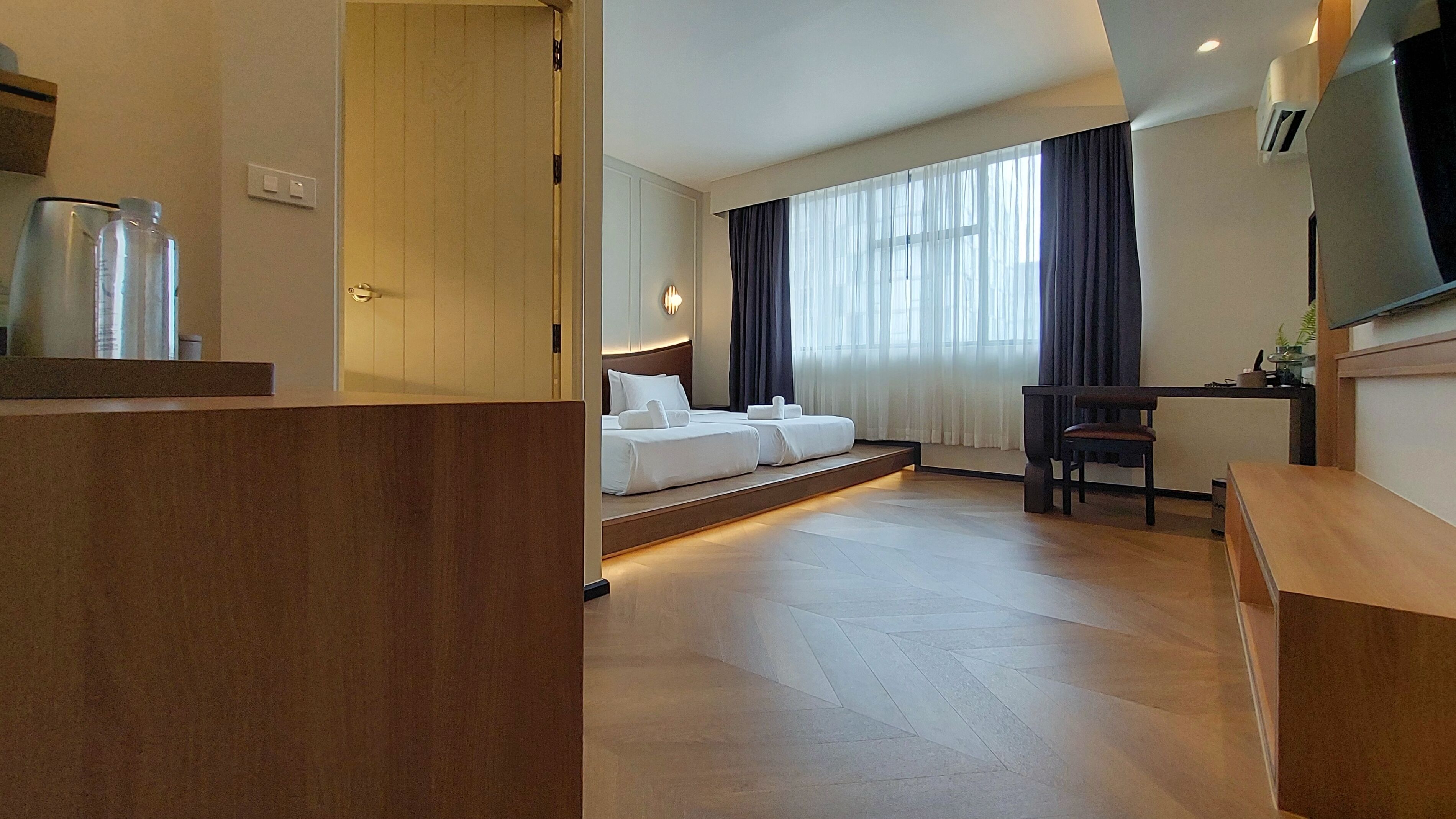 A hotel room with a bed, a desk, a chair, and a television.