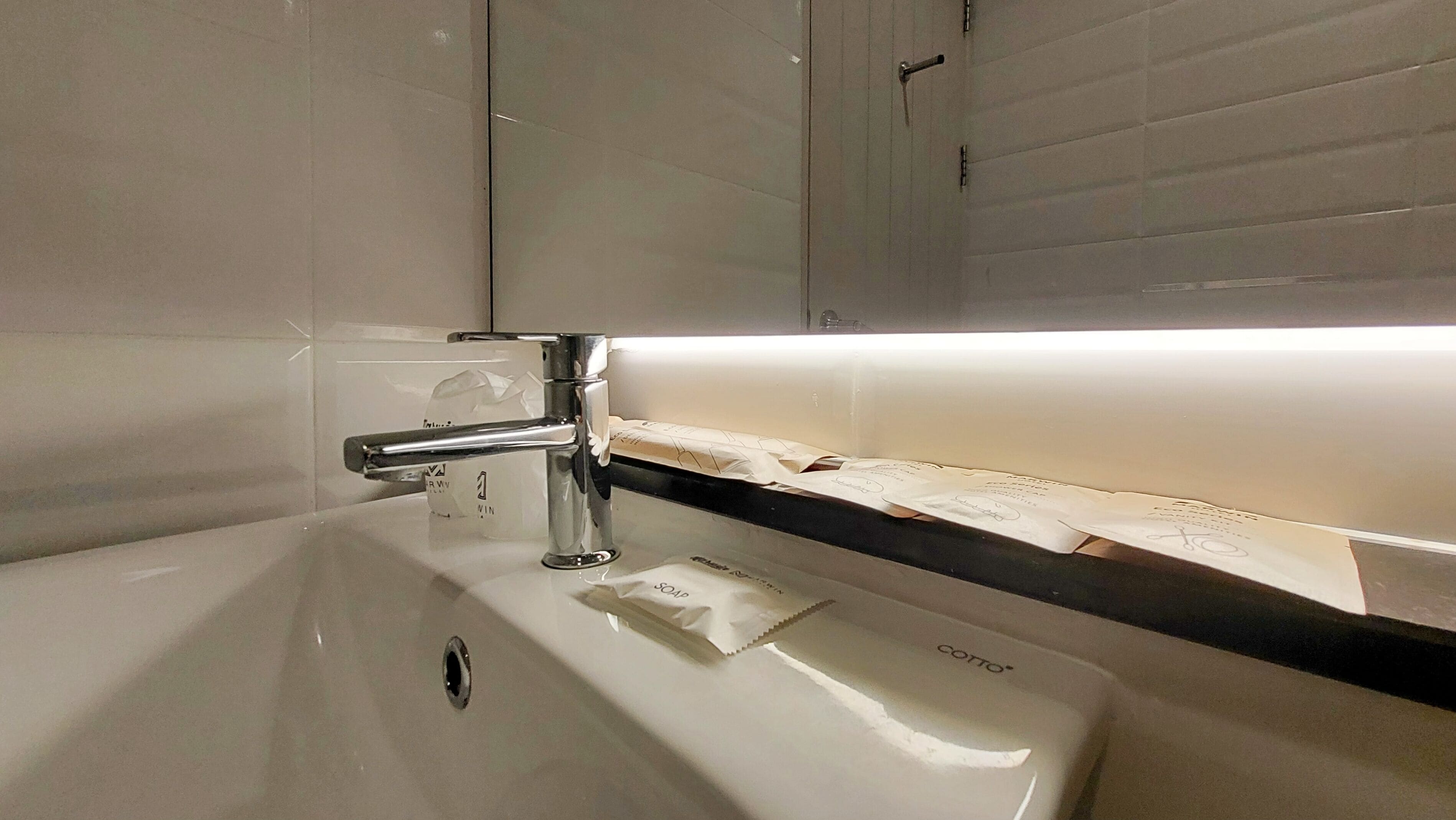 A bathroom sink with a chrome faucet, a soap dispenser, and a towel rack.