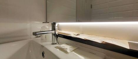 A bathroom sink with a chrome faucet, a soap dispenser, and a towel rack.