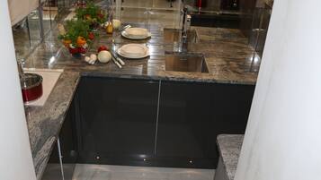 A kitchen with granite countertops, a stainless steel sink, and a black backsplash.