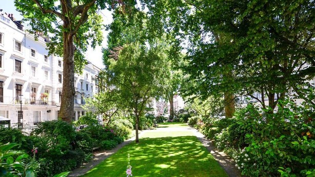 Een verzorgde tuin met een duidelijk pad, omringd door weelderig groen en bomen.