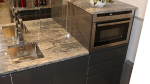 Een moderne keuken met een roestvrijstalen spoelbak, een ingebouwde oven en een granieten aanrecht.