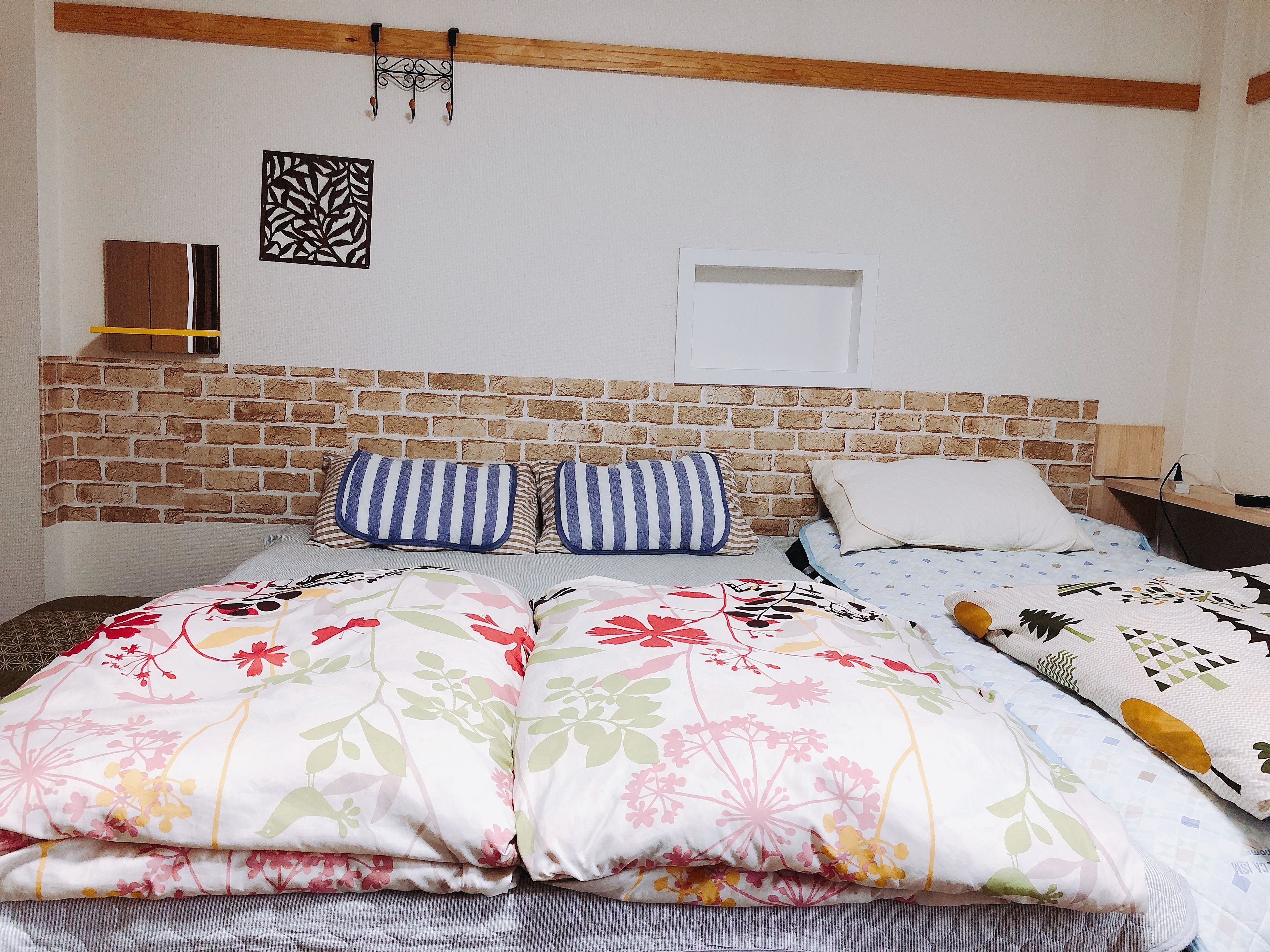 A bed with floral bedding, a brick headboard, and a wall-mounted light fixture.