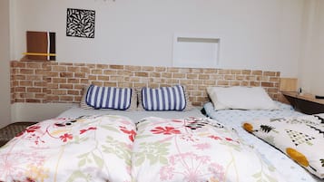 A bed with floral bedding, a brick headboard, and a wall-mounted light fixture.