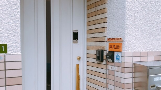 A white door with a vertical handle, a small window, and a mailbox on the wall. - Ryokoheya Hankyukan (Osaka)
