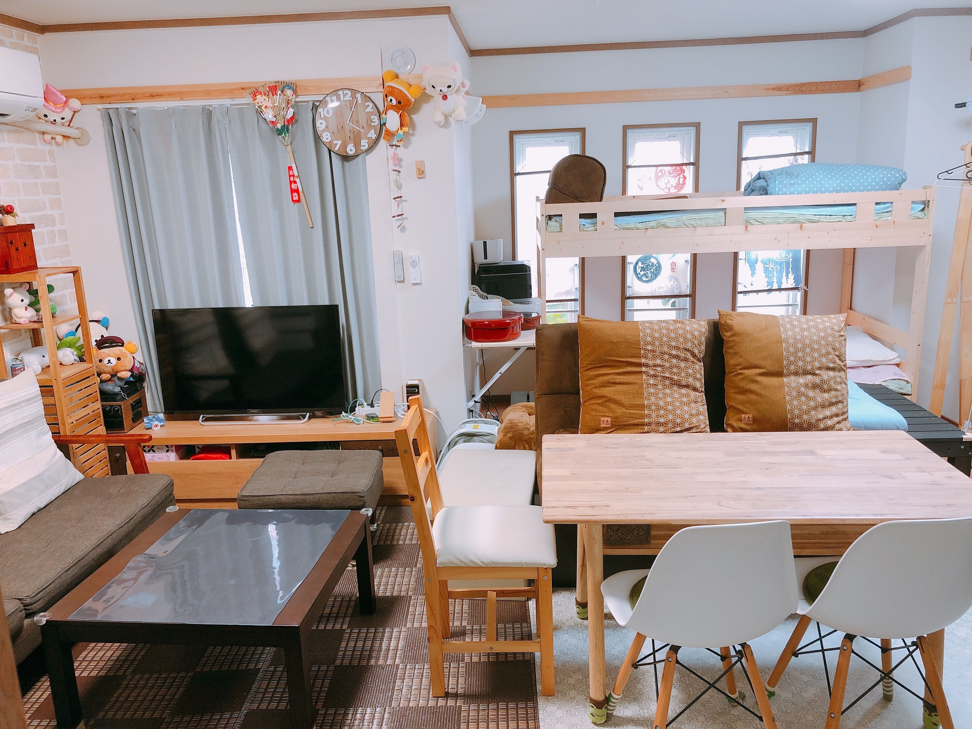 A cozy living room with a TV, sofa, bunk bed, and a dining table with chairs.