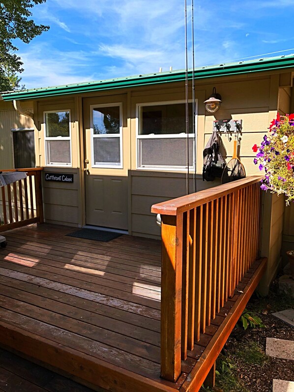 A cabin with a wooden deck, a green roof, and a sign reading "Cottage Cabin".