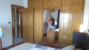 A bedroom with a bed, a wardrobe, and a mirror.