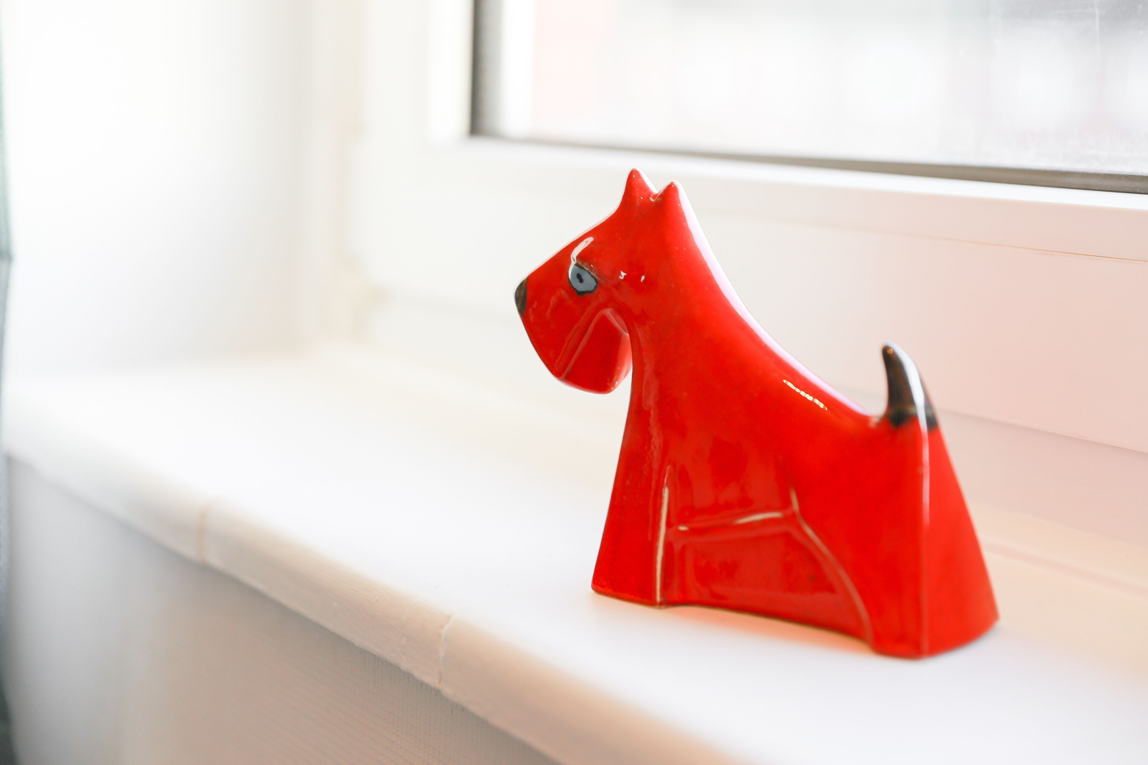 A red horse-shaped object on a white ledge by a window.