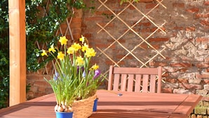Una mesa de madera con una cesta tejida que contiene flores amarillas y una maceta azul.