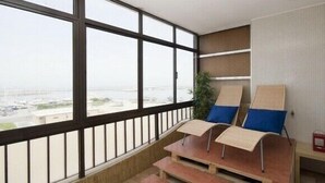 A balcony with a view of the city, a small table, and two lounge chairs with cushions.