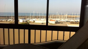 A view from a window with a balcony, overlooking a marina with numerous boats.