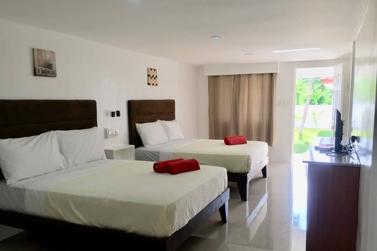 Habitación de hotel con dos camas, un escritorio y vistas al exterior.