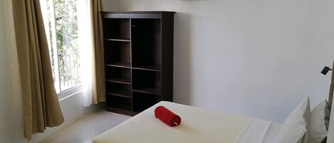 Habitación de hotel con cama, armario, ventilador de techo y aire acondicionado.