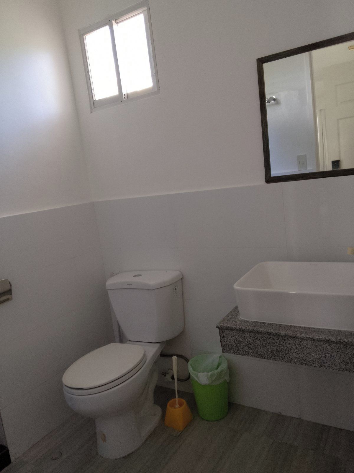 A bathroom with a toilet, a sink, and a mirror.