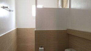 A bathroom with a toilet, a sink, and a shower area. - Heartland Hotel Service and Apartments (Panglao)