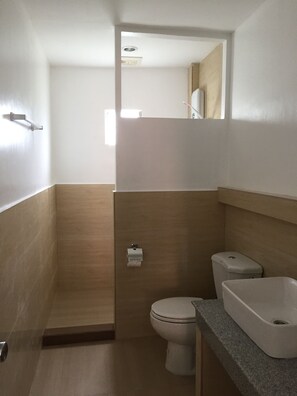 Une salle de bain comprenant des toilettes, un lavabo et un espace douche.