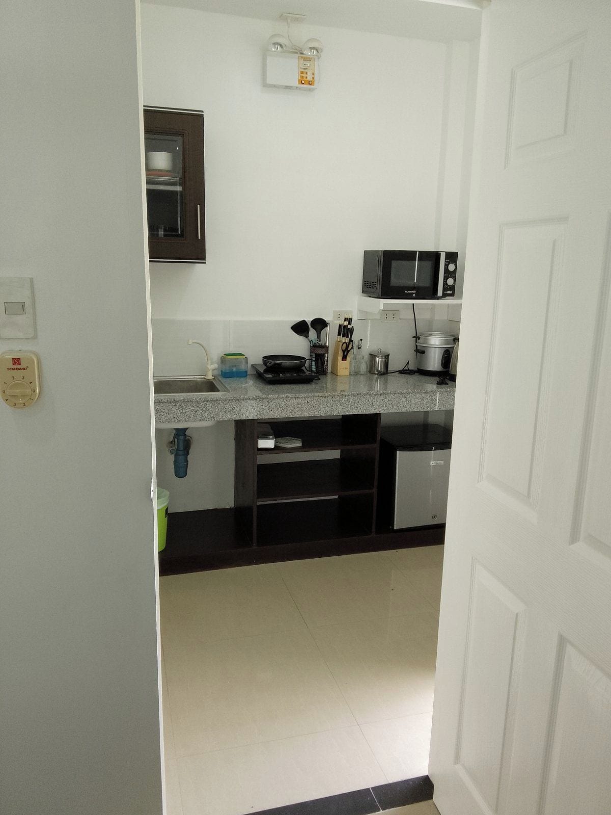 A kitchen with a microwave, stove, and various utensils.