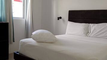 Un dormitorio con cama, ventilador de techo, aire acondicionado y ventana con cortinas.