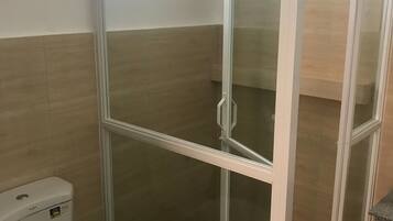 A bathroom with a toilet, a shower enclosure, and a window.