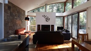 Una sala de estar moderna con una pared de piedra, una chimenea, un sofá y un comedor con un banco.