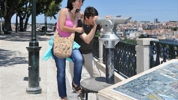 Un couple utilisant un télescope sur un pont surplombant une ville.