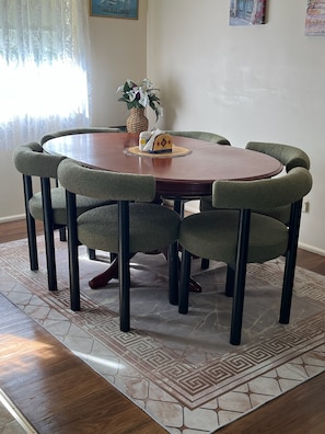 A round dining table with six chairs, a woven placemat, and a small decorative item on the table.