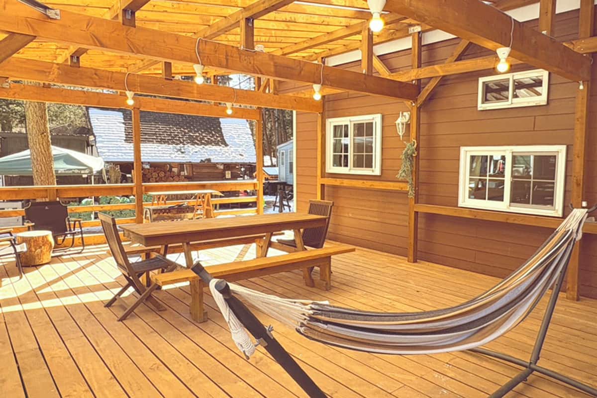 Eine Holzterrasse mit einer Hängematte, Picknicktischen und Bänken.
