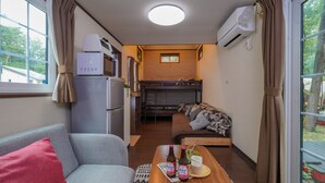 A compact room with a sofa, a small dining table with bottles, a microwave, a refrigerator, a bunk bed, and a window with curtains. - Shimizu Kuniaki’s Paradise of Forest and Lake (Fujikawaguchiko)
