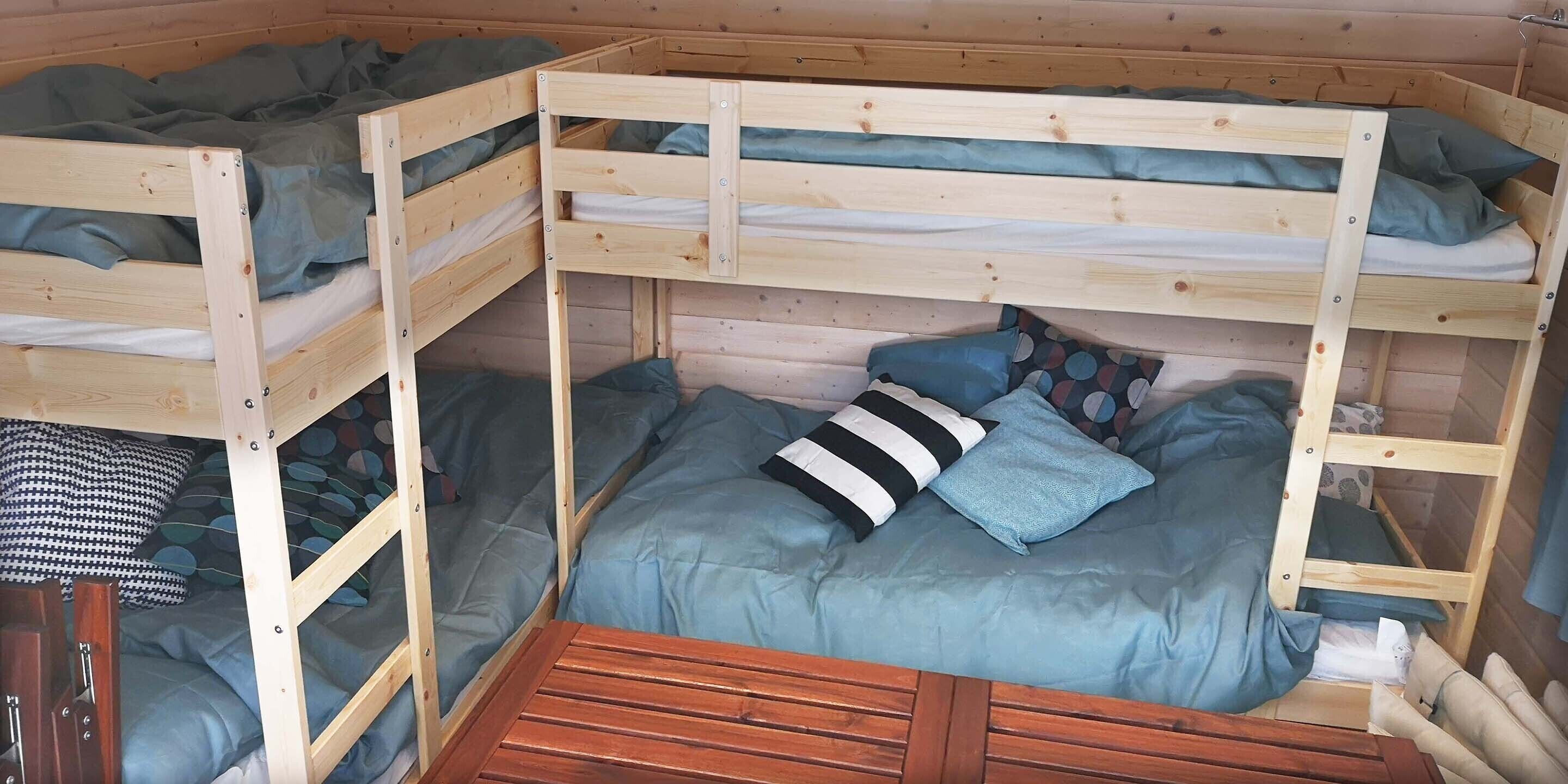 A wooden bunk bed room with blue bedding and pillows.