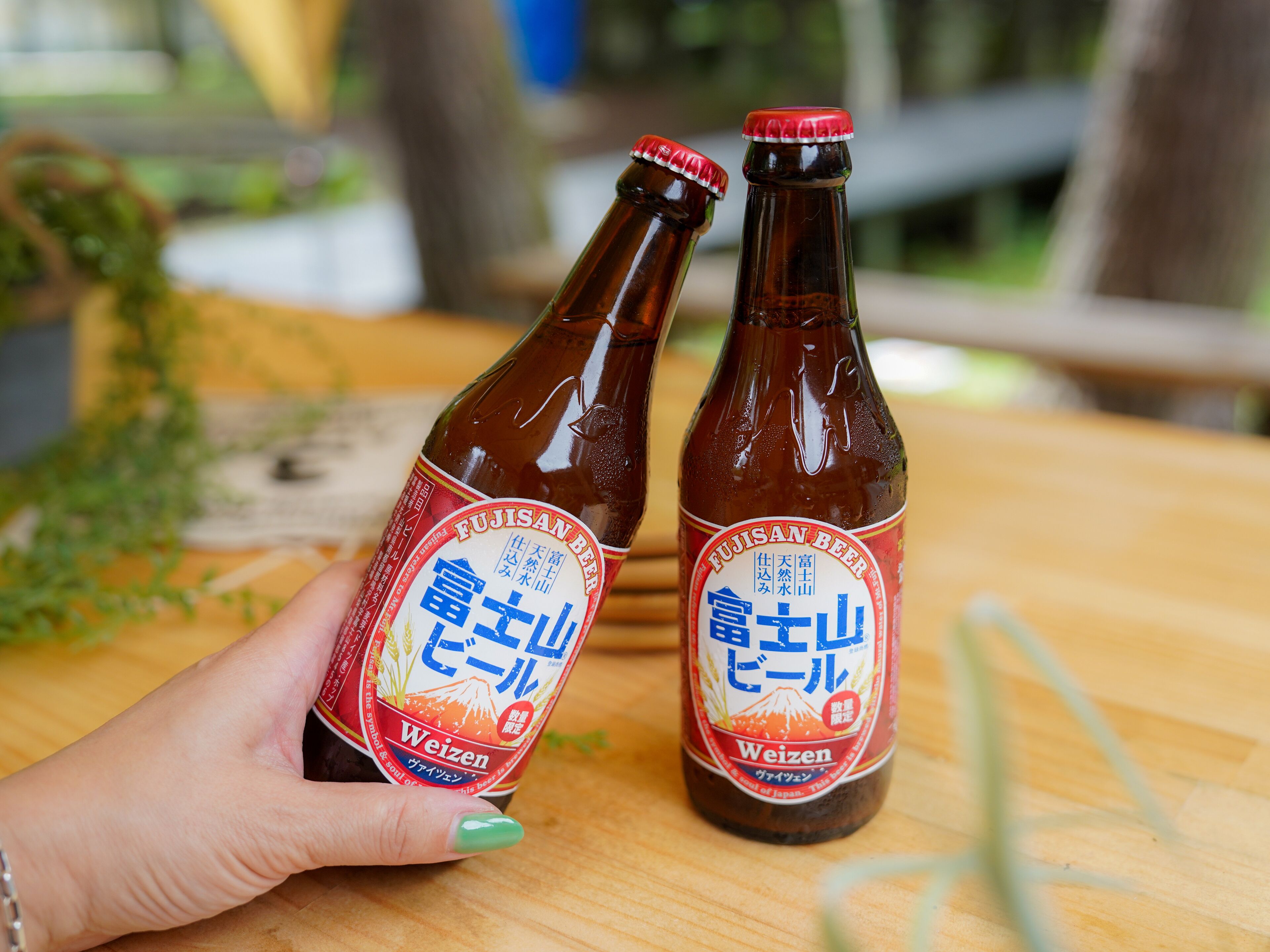 Twee bierflesjes met etiketten, geplaatst op een houten ondergrond.