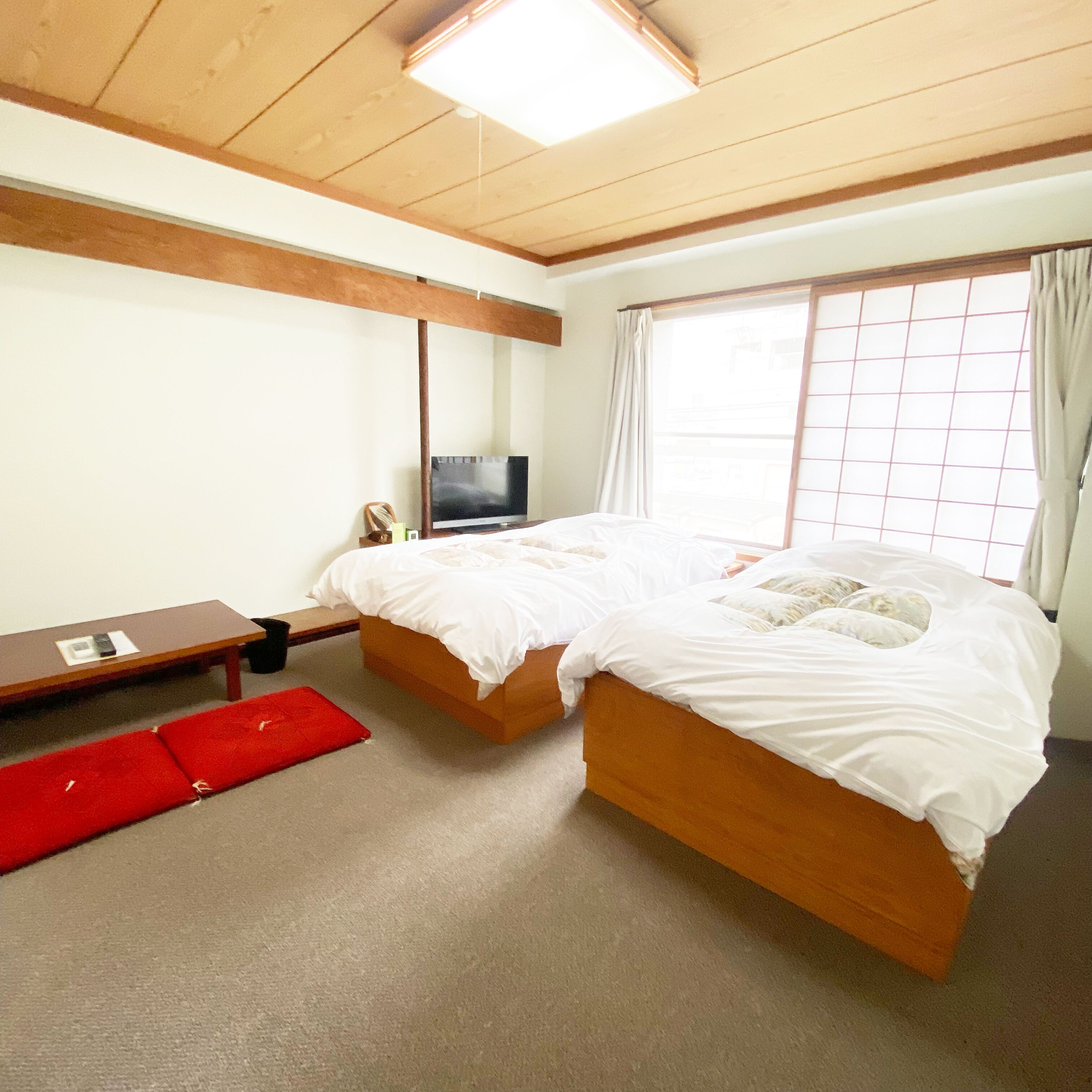 Une chambre à coucher avec un lit, une télévision, une table et une fenêtre avec des rideaux.