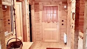 Un intérieur en bois avec un tapis rouge, des meubles en bois, un panier et un luminaire suspendu.