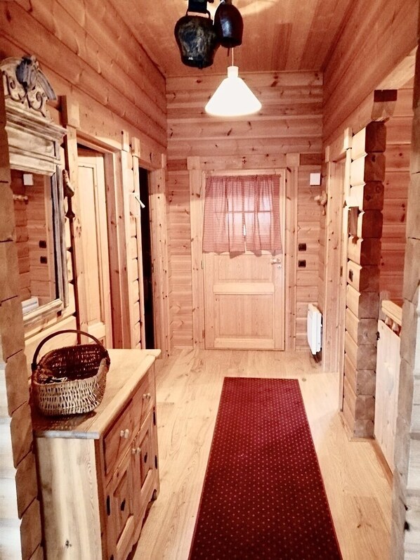 A wooden interior with a red carpet, wooden cabinets, a basket, and a hanging light fixture.