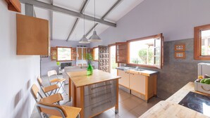 Eine moderne Küche mit Holzausstattung, einer zentralen Kochinsel und einem Essbereich mit Stühlen.