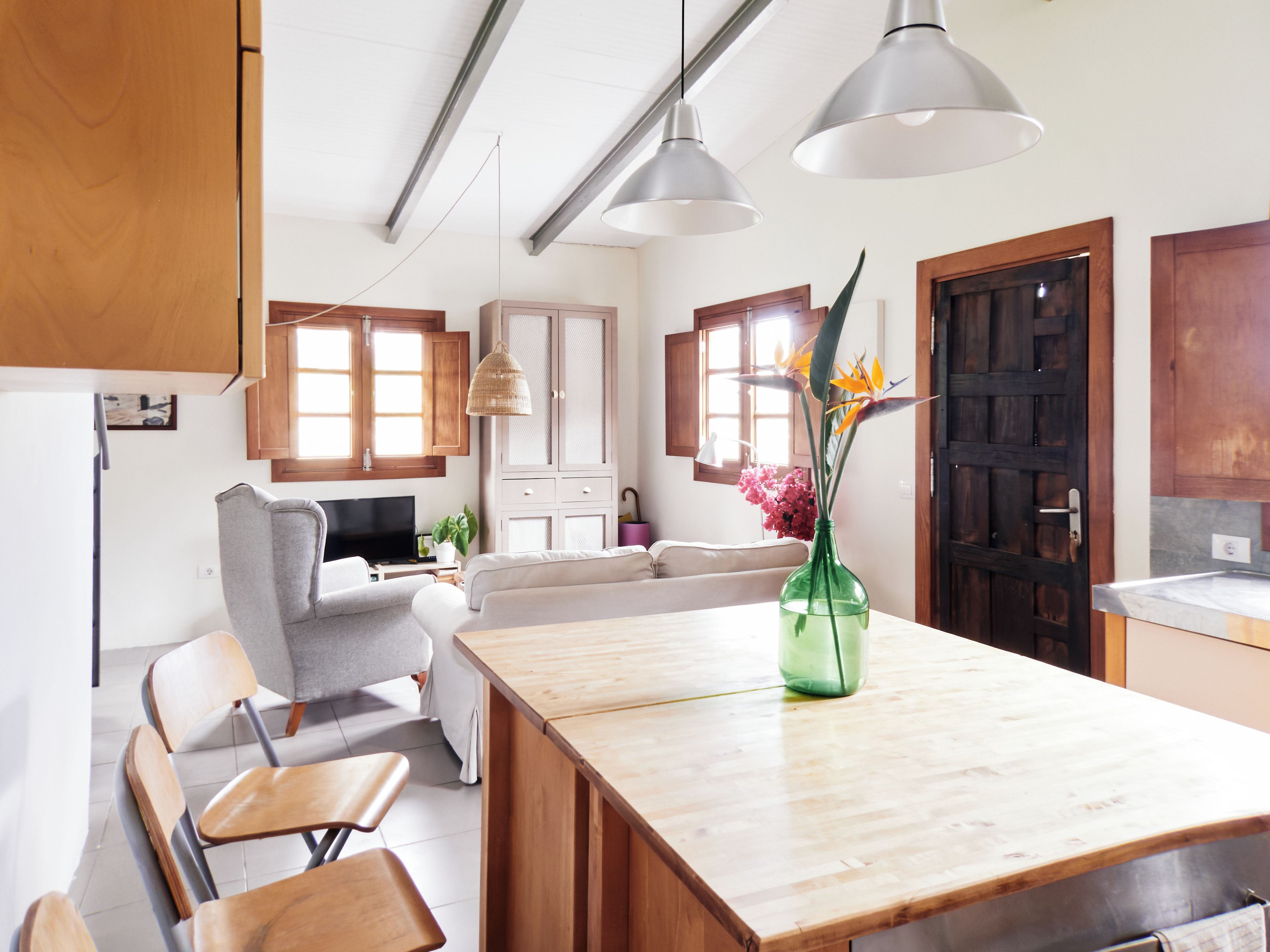 Una cucina moderna con mobili in legno, un tavolo da pranzo e lampade a sospensione.